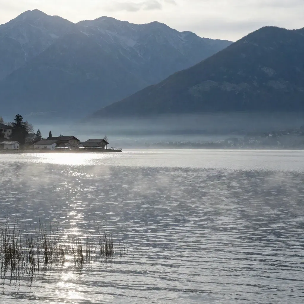 Lac d’Annecy calme, montagnes alpines en couches et rive claire sous une lumière douce.